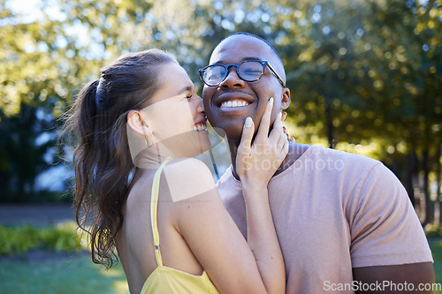 Image of Summer, love and laugh with an interracial couple bonding outdoor together in a park or garden. Nature, diversity and romance with a man and woman hugging while on a date outside in the countryside