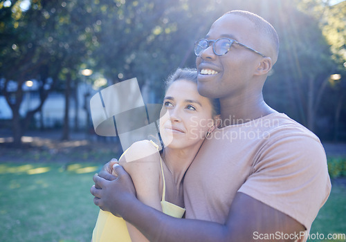 Image of Interracial couple, hug and park with smile, thinking or love for bonding, together and vision of future. Multicultural relationship, black man and woman for happiness, outdoor and diversity on grass