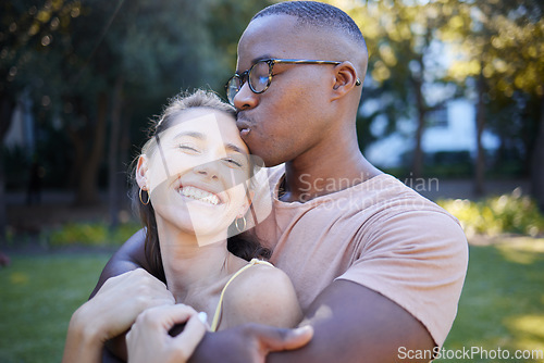 Image of Interracial, couple hug and kiss in park, date outdoor in nature, happiness with love and commitment in relationship. Trust, support and happy woman with smile, black man content with fresh air