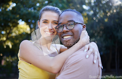 Image of Portrait, couple on a date and hug with love in nature, outdoor in park with commitment in interracial relationship. Trust, support and happy people, black man and woman smile on face with fresh air