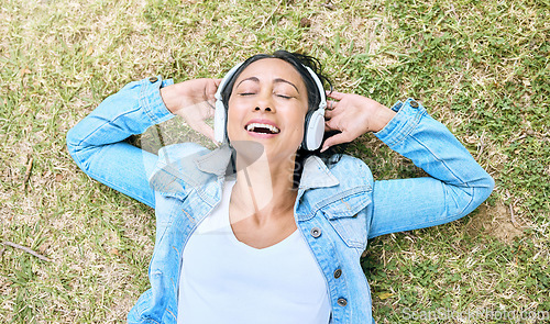 Image of Music headphones, top view and woman relax at park outdoors. Peace, calm and happy, carefree and mature female streaming radio, podcast or audio song while relaxing or resting on grass in nature.