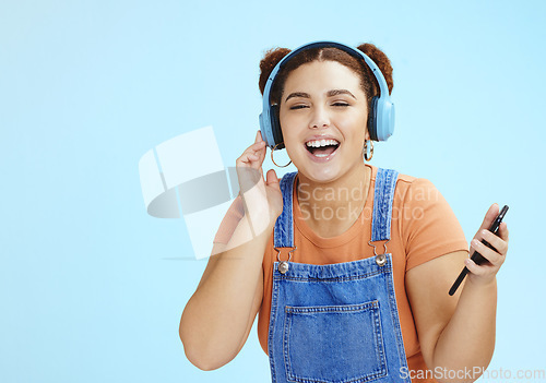 Image of Headphones, woman student and phone music streaming of a gen z model with blue studio background. Isolated, happy and freedom of a person listening to web radio and podcast audio with a smile