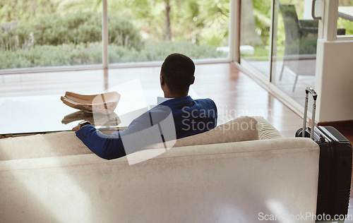 Image of Thinking, immigration and vision of businessman on a couch or sofa in a hotel sitting looking at a window. Rear view, travel and back of professional corporate worker waiting in lounge or living room