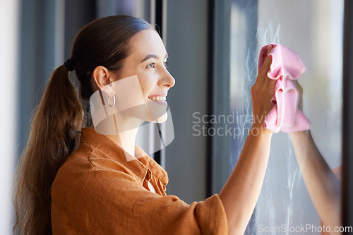 Image of Woman cleaning window or wipe glass with a cloth in an apartment, home or house and washing bacteria. Disinfection, hygiene and smiling female removing dirt or dust in an office by doing housework