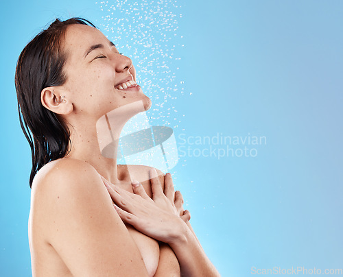 Image of Woman, happy and shower, water and cleaning body for hygiene against blue studio mockup background. Asian female, model and shortless while showering, happiness and clean with smile and bathroom