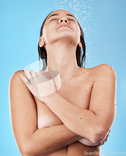 Image of Shower, body and woman in the nude with water for cleaning, grooming and hygiene against a blue studio background. Skin, wellness and happy Asian model with peace, calm and relax while showering