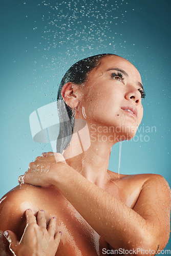 Image of Shower, water and cleaning with a woman washing in studio on a blue background for hygienic body care. Bathroom, skincare and beauty with a young female cleansing for natural skin treatment