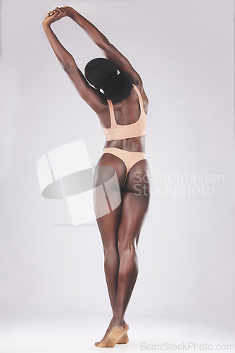 Image of Back, body and fit black woman stretch from behind on a white studio background. Shape, fitness and stretching African American female rearview for health, wellness and skincare or beauty