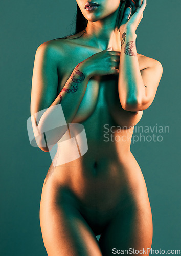 Image of Neon, studio and body of naked woman on blue background for sensuality, seductive and nude freedom. Art deco, sexy female and torso of attractive girl with tattoo, erotic pose and glowing skin