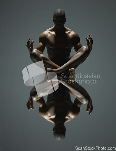 Image of Black man, meditation and mirror reflection on dark background for spiritual wellness or symmetry. Portrait of a naked, nude or bare African American male model sitting and meditating doppelganger