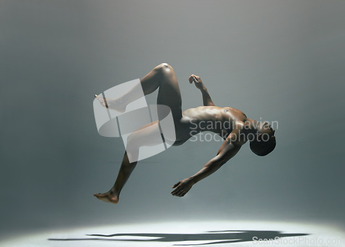 Image of Nude, body and man in studio for art, levitating and creative, artistic against a grey background. Fine art, model and naked male floating, light and posing bare, falling and erotic art deco isolated