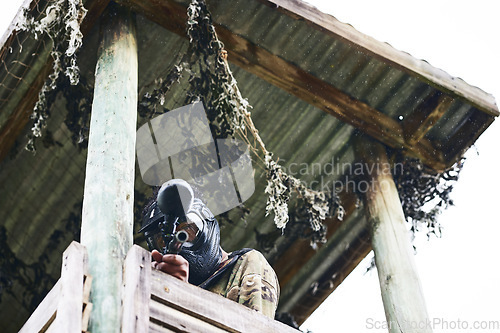 Image of Paintball scout, tower and aiming for tango, enemy or opponent in sight ready to fire for victory, win or match point. Soldier in focus standing in fort with gun for game, military or army defense