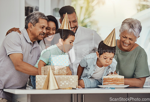 Image of Birthday, celebration and twin children with family blowing the candles on a cake at their party. Happy, excited and kids with their parents and grandparents in the kitchen of their home to celebrate