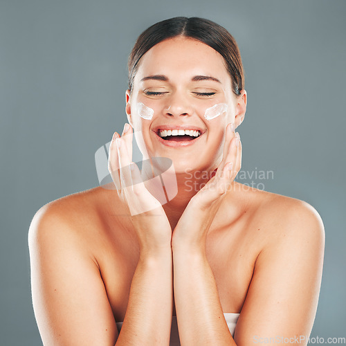 Image of Woman apply cream for face, happy laugh and beauty, skincare and moisturizer isolated on studio background. Sunscreen, lotion and healthy skin with glow, wellness and facial treatment with happiness