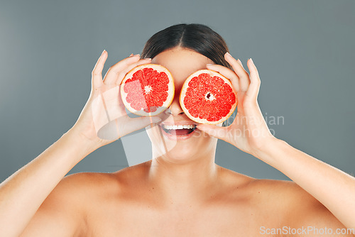 Image of Fruit eyes, woman and beauty model with grapefruit for skincare, wellness and health. Studio background, young person and happiness holding healthy food for vitamin c, diet and dermatology support