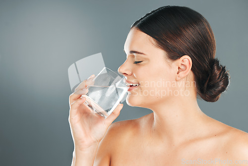 Image of Woman, glass and drinking water for hydration, skincare or nutrition for sustainability against grey studio background. Happy female with smile in beauty for fresh clean sustainable liquid on mockup