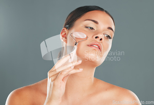 Image of Face massage with roller, woman and skincare with beauty tools and healthy skin isolated on studio background. Natural cosmetics, glow and makeup with hand, manicure and wellness for cosmetic care