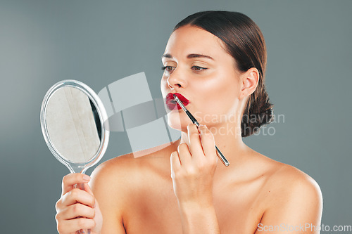 Image of Lipstick, mirror and woman face getting ready with cosmetics and makeup brush. Mouth, female and beauty model looking at reflection with cosmetic tool with isolated studio background and lips product