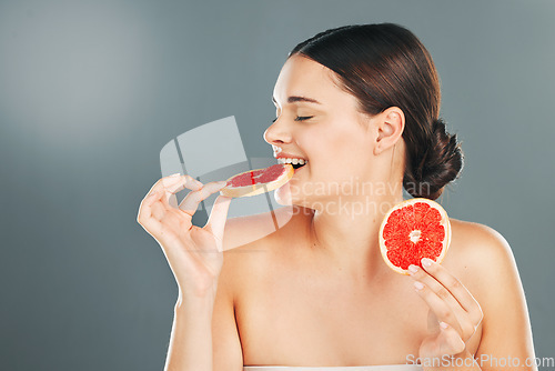 Image of Grapefruit, skincare and woman eating on studio background for wellness benefits. Beauty model diet with citrus fruits, natural detox and nutrition of healthy food, happy face and smile for vitamin c