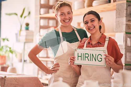Image of Portrait, hiring and sign with woman friends in a small business pottery workshop for recruitment. Startup, management or owner with a female entrepreneur and friend holding a notice in their studio