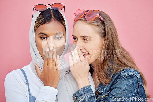 Image of Woman, friends and gossip in shock for secret whisper in ears against pink studio background. Women sharing secrets, rumor or surprise whispering in the ears for hidden story or discount announcement