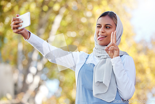 Image of Selfie, peace and Islamic woman outdoor, silly face or confident with casual outfit, happiness or joy. Muslim female, lady in nature or smartphone to share photo, social media or connection with sign