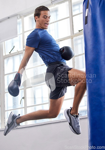 Image of Gym, jump and kick of boxer man for sports workout, training and athlete practice with equipment. Energy, focus and strength of martial arts fighter at kickboxing fitness club with punching bag.