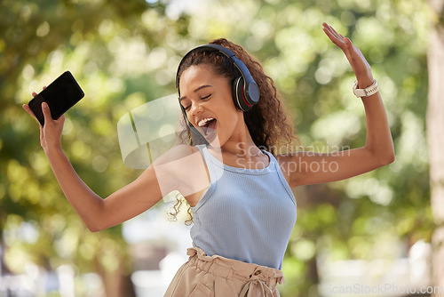 Image of Phone, music and dance with a black woman listening to the radio in the park during summer while feeling free. Freedom, sing and dancing with an attractive young female streaing audio in a garden