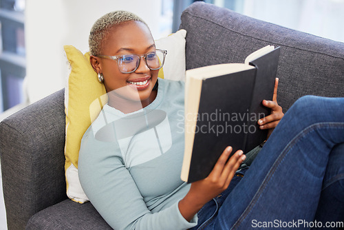 Image of Black woman, relax smile and reading book on sofa in living room for calm peace, happiness and studying in home. Young african girl, happy student and relaxing with notebook or university textbook