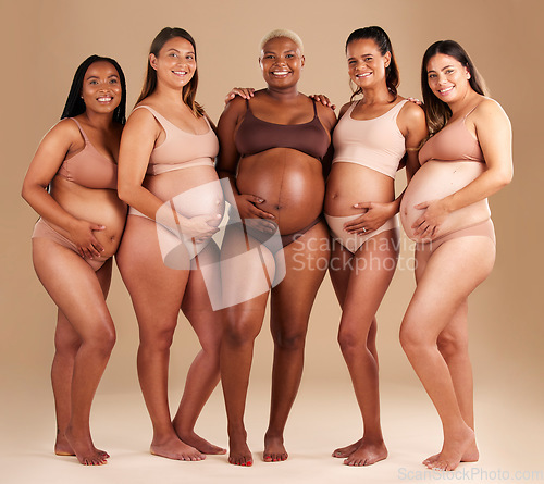 Image of Pregnancy, diversity and portrait of friends in studio for community, motherhood and prenatal wellness. Maternity, love and pregnant women showing their baby bump stomach together by beige background