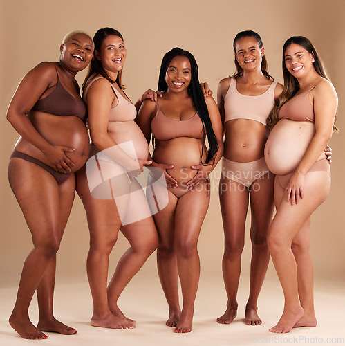 Image of Pregnancy, beauty and portrait of friends in a studio for diversity, motherhood and prenatal wellness. Maternity, love and pregnant women showing their baby bump stomach together by beige background.