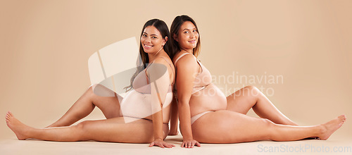 Image of Friends, pregnancy and studio portrait for underwear, smile and women sitting together for support on floor. Happy future mom, pregnant or solidarity for health, love or healthy stomach by background