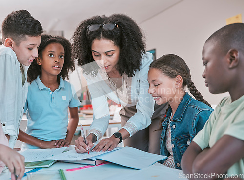 Image of Female teacher in classroom with children, helping girl student with schoolwork and writing in book. Diversity in education, educator reading kids notebook and group learning together for assessment