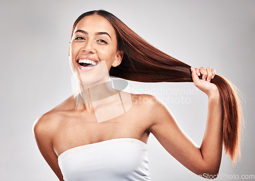 Image of Happy, woman and portrait of healthy hair in studio for beauty, salon and care on grey background. Face, hold and pull by girl model smile for luxury, strong and shiny keratin results isolated