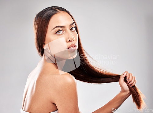 Image of Portrait, beauty and woman with strong hair in studio for salon, hair care and serious on grey background. Face, shine and pull by girl model relax for wellness and shiny keratin result isolated