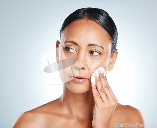 Image of Face, beauty and senior woman with cotton in studio isolated on gray background. Thinking, cosmetics product and mature female model with facial pad to remove makeup for cleaning, skincare or hygiene