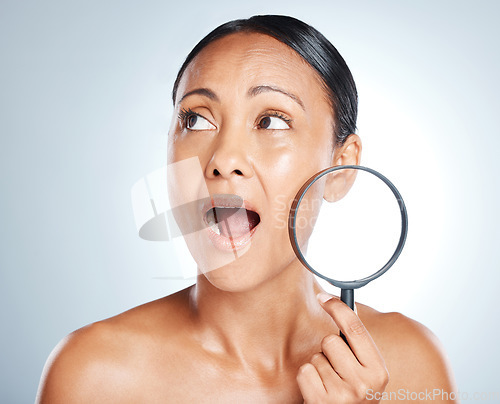 Image of Face, beauty and surprise of woman with magnifying glass in studio isolated on gray background. Wow, makeup cosmetics and mature female with lens, thinking or shocked after skincare facial treatment