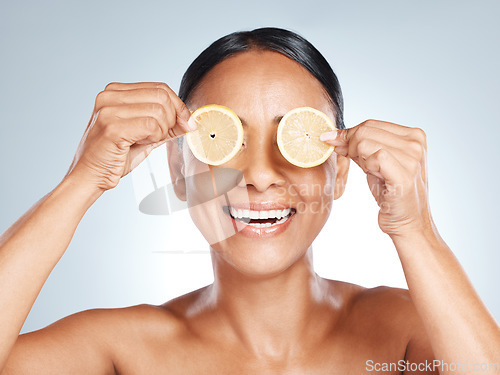 Image of Lemon, woman face and vitamin c skincare, beauty or clean wellness on studio background. Happy model, smile and citrus fruit of natural cosmetics, detox and facial nutrition of healthy aesthetic glow