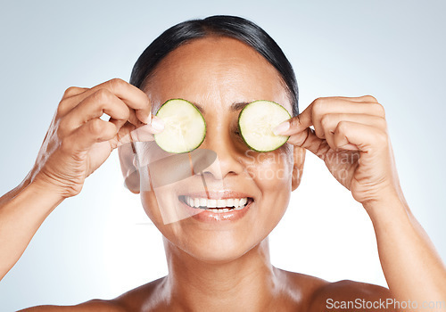 Image of Cucumber, woman face and natural skincare, beauty or clean wellness on studio background. Happy model, eyes and green fruits cosmetics, detox and facial nutrition with vitamin c for healthy aesthetic
