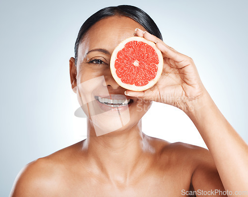 Image of Grapefruit, woman and vitamin c beauty, portrait and skincare wellness on studio background. Happy model, face and citrus fruits for natural cosmetics, detox and nutrition for healthy aesthetic glow