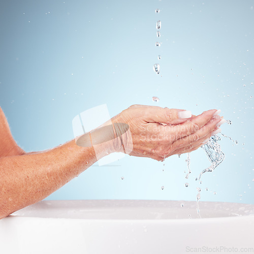 Image of Senior hands, water and wash for clean hygiene, fresh minerals or splash against a studio background. Hand of elderly holding natural liquid for skin hydration, wellness or skincare in sink or basin