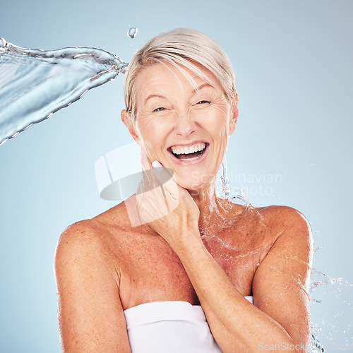 Image of Smile, shower and portrait of a woman with a water splash isolated on a blue background in studio. Grooming, hygiene and face of an excited senior model with body and self care on a backdrop