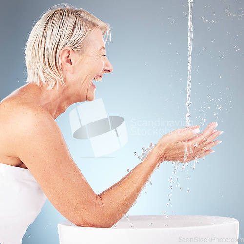 Image of Senior woman, water splash and washing hands for wellness, beauty and skincare health on studio background. Happy model, cleaning drops and body in bathroom of facial aesthetic, shower and self care