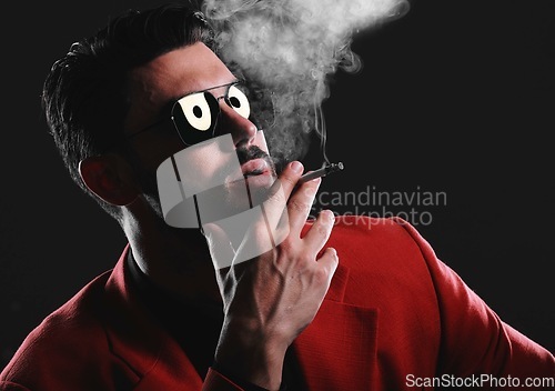 Image of Fashion, smoke and face with a man model in studio on a dark background wearing a suit for style. Smoking, mafia and edgy with a handsome young male posing on black space holding a cigarette