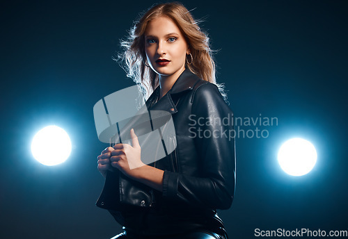 Image of Portrait, fashion and lights with a model woman in studio on a dark background wearing a leather jacket for style. Art, spotlight and trendy with an attractive young female posing on black space