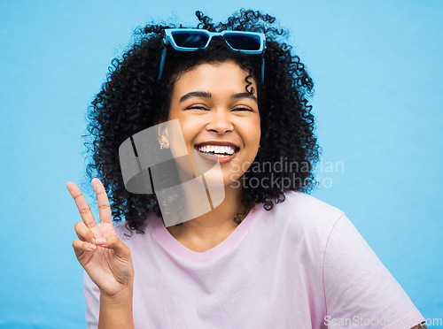 Image of Black woman, happy smile and peace sign portrait of a model isolated with blue background in a studio. Young, smiling and v hand gesture of a person feeling relax with happiness with casual style