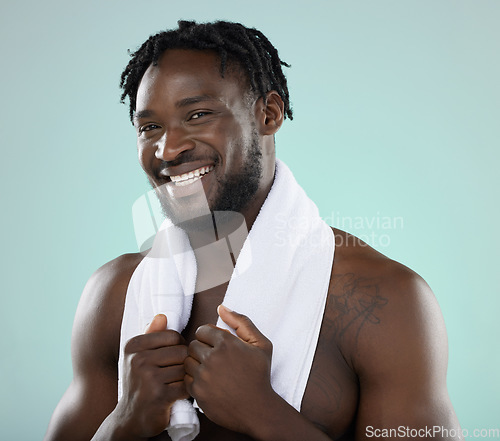Image of Man, face portrait and skin in studio with towel for hygiene and grooming. Healthy and happy black person on blue background for facial glow, cosmetics and self care with dermatology skincare brand