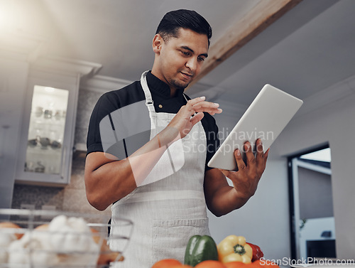Image of Man, cooking vegetables and tablet in kitchen while online with house wifi connection for learning or blog. Chef person with mobile app for online recipe for home food for vegan or healthy eating