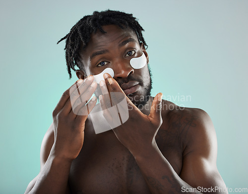 Image of Eye patch, man and face portrait for skincare, beauty and dermatology in studio. Healthy black person on blue background for facial glow, clean skin and self care with cosmetic collagen mask