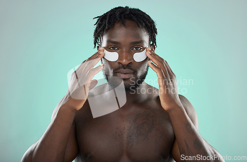 Image of Skincare, eye pads and black man in studio for healthy, cosmetic and natural face routine. Health, wellness and portrait of an African guy with a facial treatment by blue background with mockup space